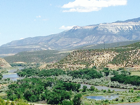 Shale stone mountain views, Blue skies with cumulus cloud, green mesa's, with Colorado River rolling through the trees